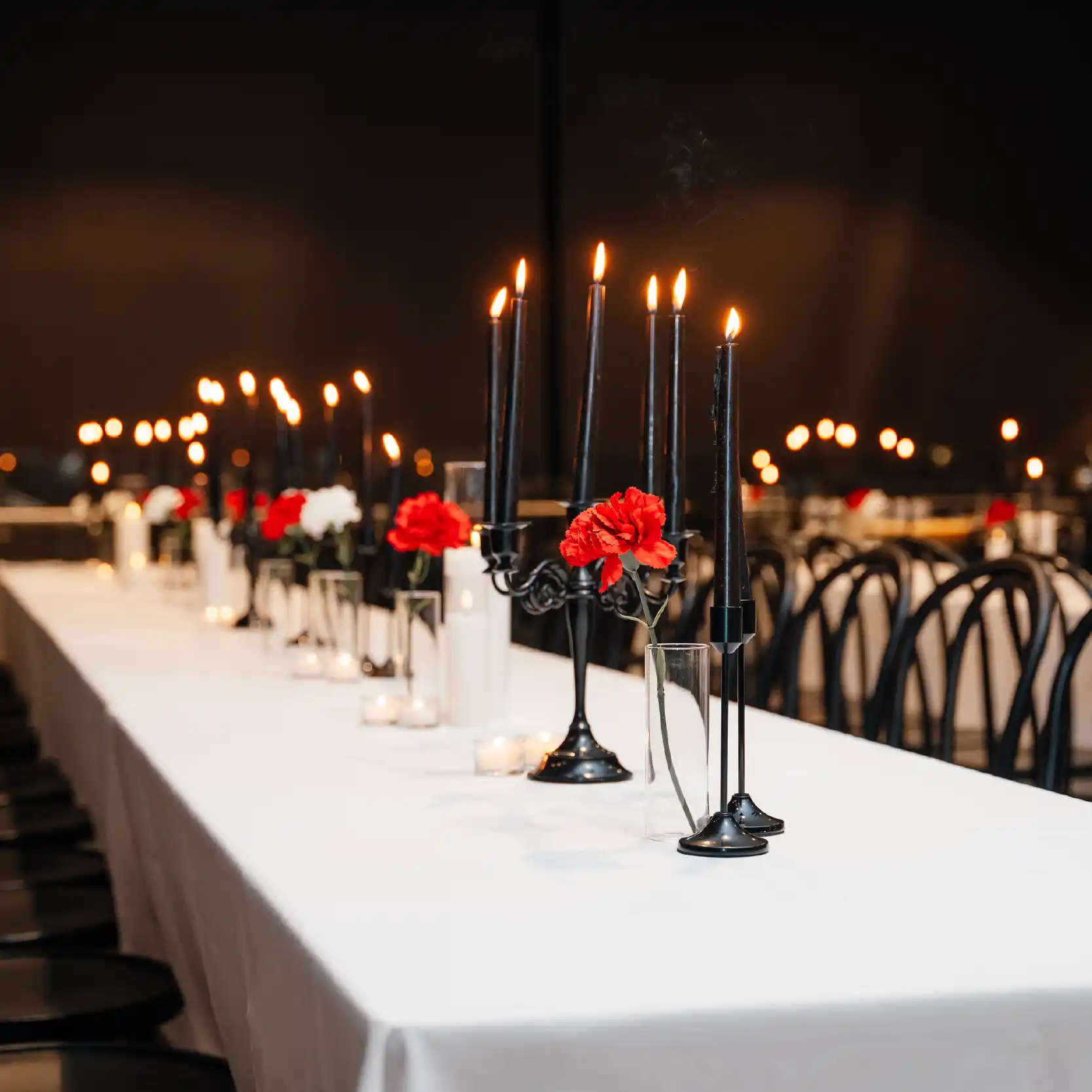 events table set up with lighted black candles and red flowers.