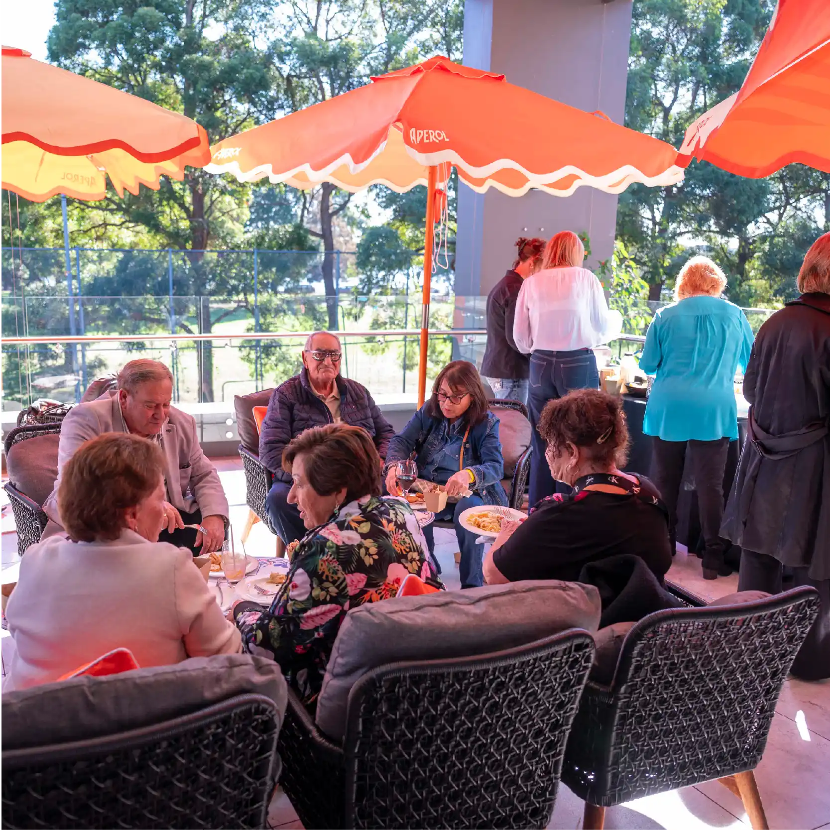 Nice balcony with orange Aperol umbrellas, and people enjoying their food