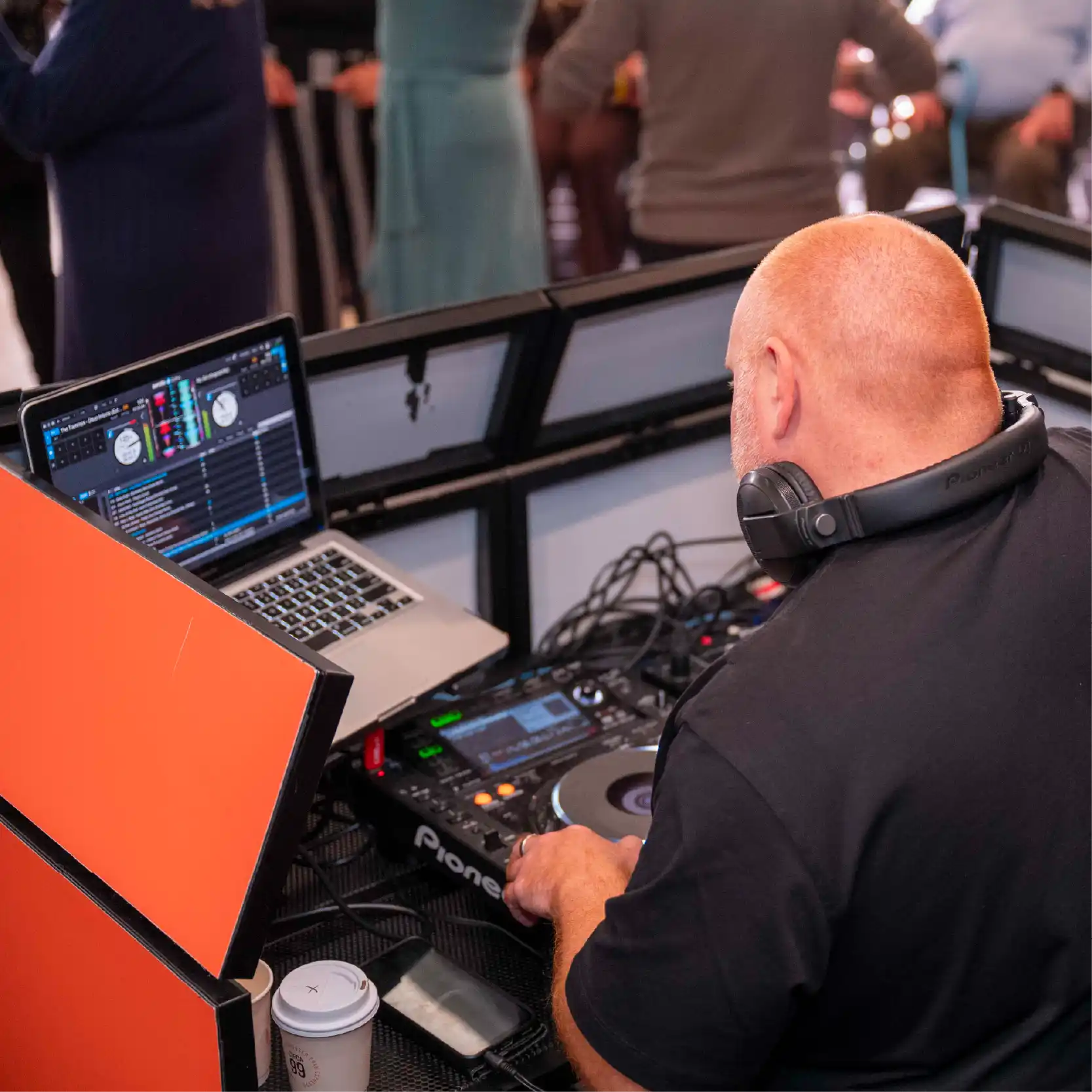 DJ playing music and people dancing at the back